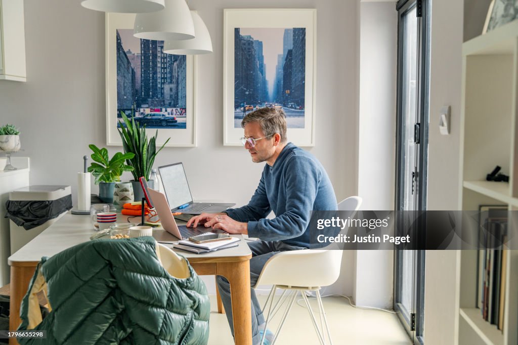 Side view of a man working from home from the dining table