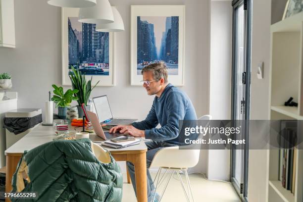 side view of a man working from home from the dining table - hand stock pictures, royalty-free photos & images