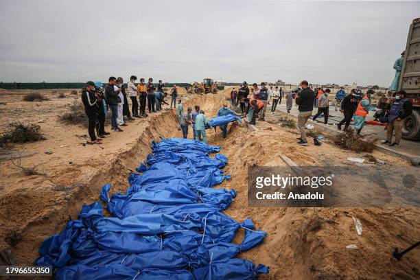 People place the bodies of dead Palestinians, who lost their lives during the Israeli attacks, in a mass grave in the cemetery in Khan Yunis, Gaza on...