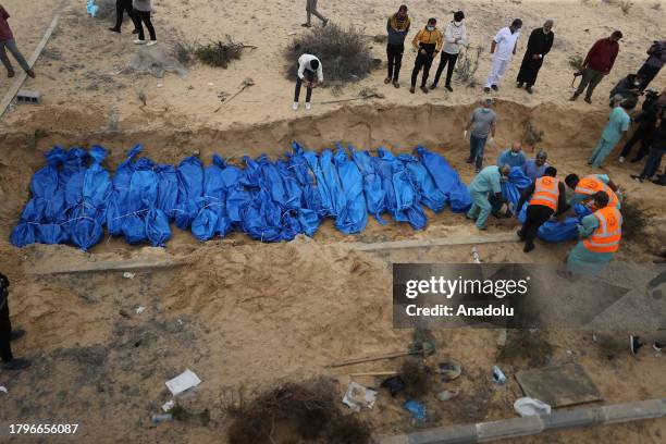 An aerial view of people placing the bodies of dead Palestinians, who lost their lives during the Israeli attacks, in a mass grave in the cemetery in...