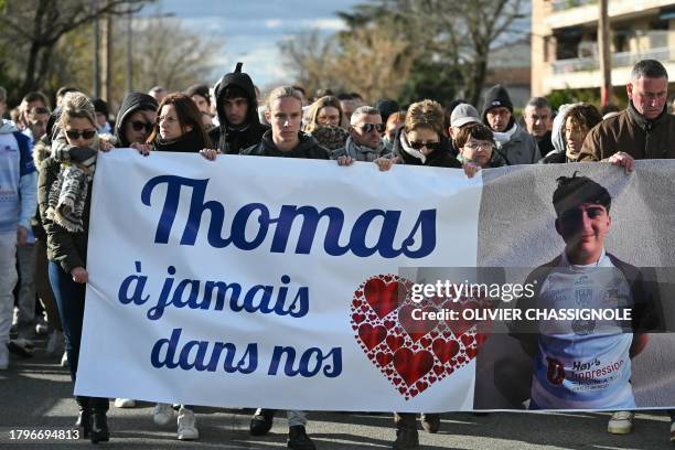 People march behind a banner which reads as "Thomas, in our hearts forever" in Romans-sur-Isere, southeastern France on November 22 as they take part...