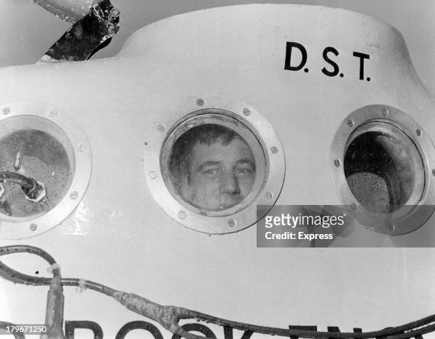 American Dan Taylor checks one of the observation ports in his yellow 20-foot submarine- just one of the innumerable routines that go with searching...