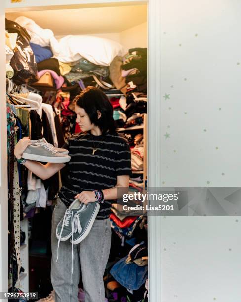 transgender non-binary teenager in their bedroom picking out clothes to wear in closet - overflowing closet stock pictures, royalty-free photos & images