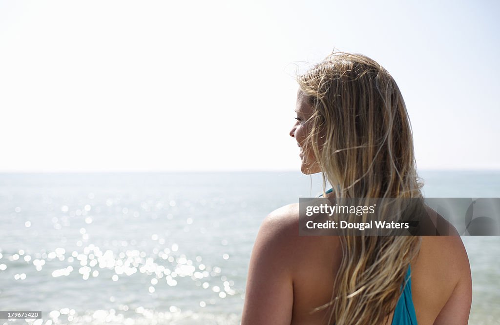 Woman smiling whilst looking out to sea.