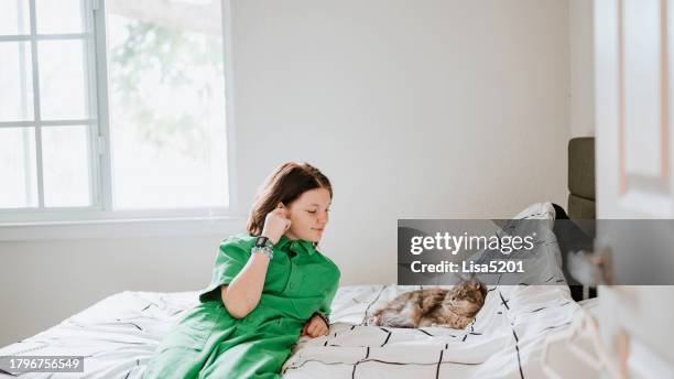 transgender non binary teenager hanging out at home in bedroom with pet cat listening to music with joy - cats musical stock pictures, royalty-free photos & images