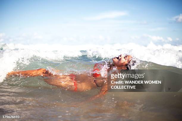 Girl in bikini dunking under waves in the surf