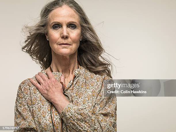 senior female with hair blowing in wind - hands on chest stock pictures, royalty-free photos & images