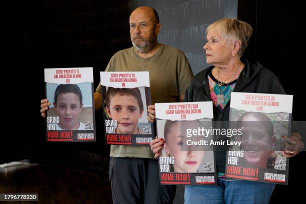 David and Varda Goldstein pose for a picture whilst holding-up photos of their 3 grandchildren, Gal, Tal and Agam, and their mother, Chen, who were...