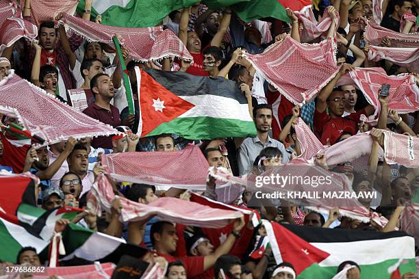 Jordanese fans wave their national flag and traditional Keffiyeh head scarfs as they watch their national team play their 2014 World Cup qualifier...