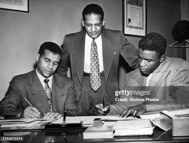 Rudolph J Thomas , Director of the Harlem Branch YMCA looks on as Roy Campanella , Catcher and Jackie Robinson Second Baseman for the Brooklyn...