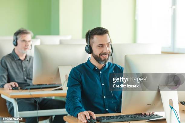mid adult man in call center smiling at camera - communication occupation stock pictures, royalty-free photos & images