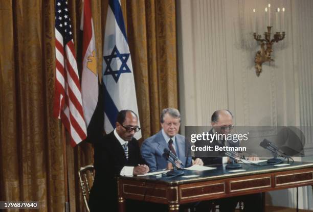 Egyptian President Anwar Al Sadat , US President Jimmy Carter and Israeli Prime Minister Menachem Begin seated at a table during the signing ceremony...