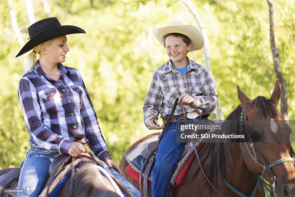 Young cowboy and cowgirl riding horses during trail ride