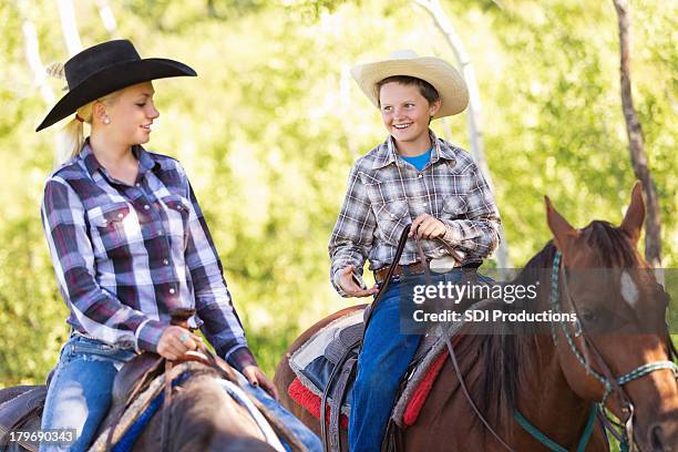 Young Cowboy And Cowgirl Riding Horses During Trail Ride High-Res Stock Photo