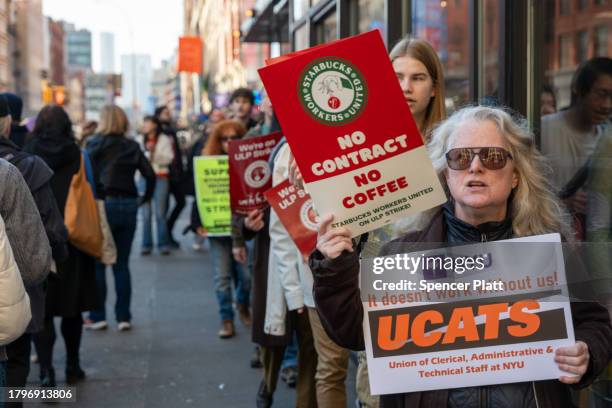 People picket outside of a Starbucks store in New York's East Village as Starbucks Workers United have announced that they are waging the company's...