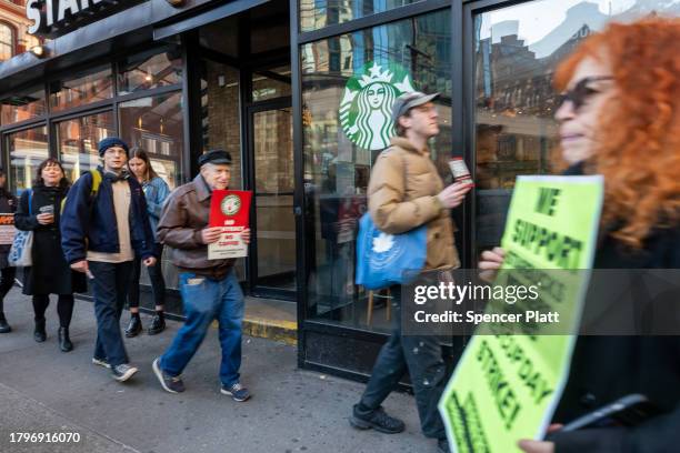 People picket outside of a Starbucks store in New York's East Village as Starbucks Workers United have announced that they are waging the company's...