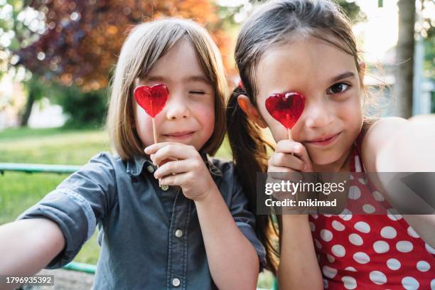 two children making selfie and eating lollipop. kids are having fun in the park. - girl lollipops stock pictures, royalty-free photos & images