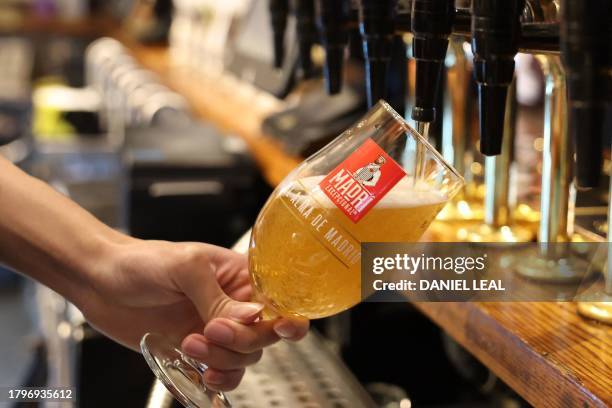 Bar worker pours a pint of lager at a pub in central London on November 22, 2023. Britain's Conservative government launched plans Wednesday to...