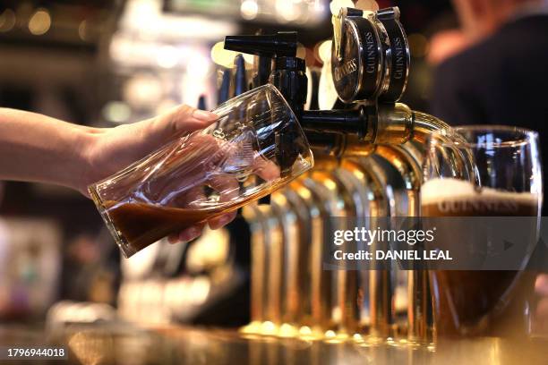 Bark worker pours a pint of Guinness at the bar in pub in central London on November 22, 2023. Britain's Conservative government launched plans...