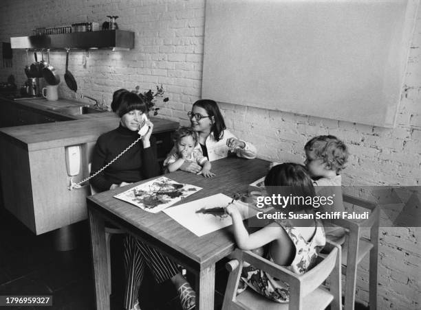 Emily Samton speaks on the telephone as she sits with her children at the table designed by her husband, American architect Peter Samton, in the...