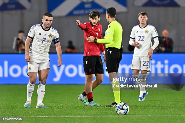 Khvicha Kvaratskhelia of Georgia reacts towards referee, Aleksandar Stavrev after scoring the teams first goal as John McGinn of Scotland looks...