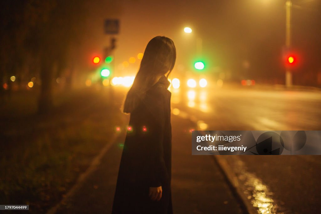 Frau auf nächtlichem Stadtstraßenhintergrund.