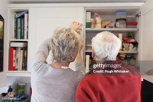 senior couple checking kitchen cupboards - pantry stock pictures, royalty-free photos & images