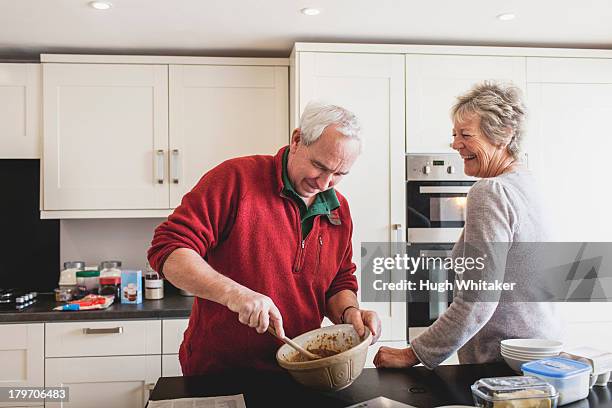 senior couple baking in kitchen - woman front and back stock-fotos und bilder