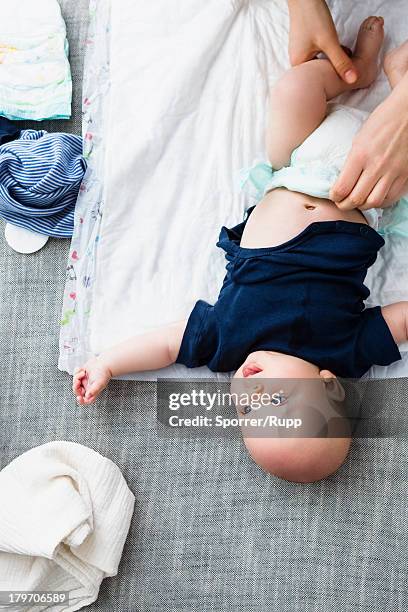 person changing baby boy's nappy, overhead view - baby changing mat stock-fotos und bilder