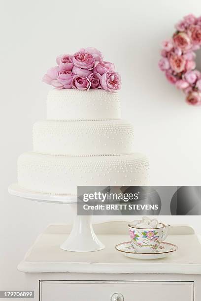 three tiered wedding cake with pink floral arrangement and cup and saucer - cake tier stock pictures, royalty-free photos & images