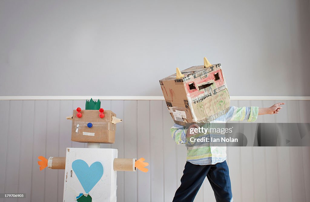 Boy with box covering head and homemade toy robot