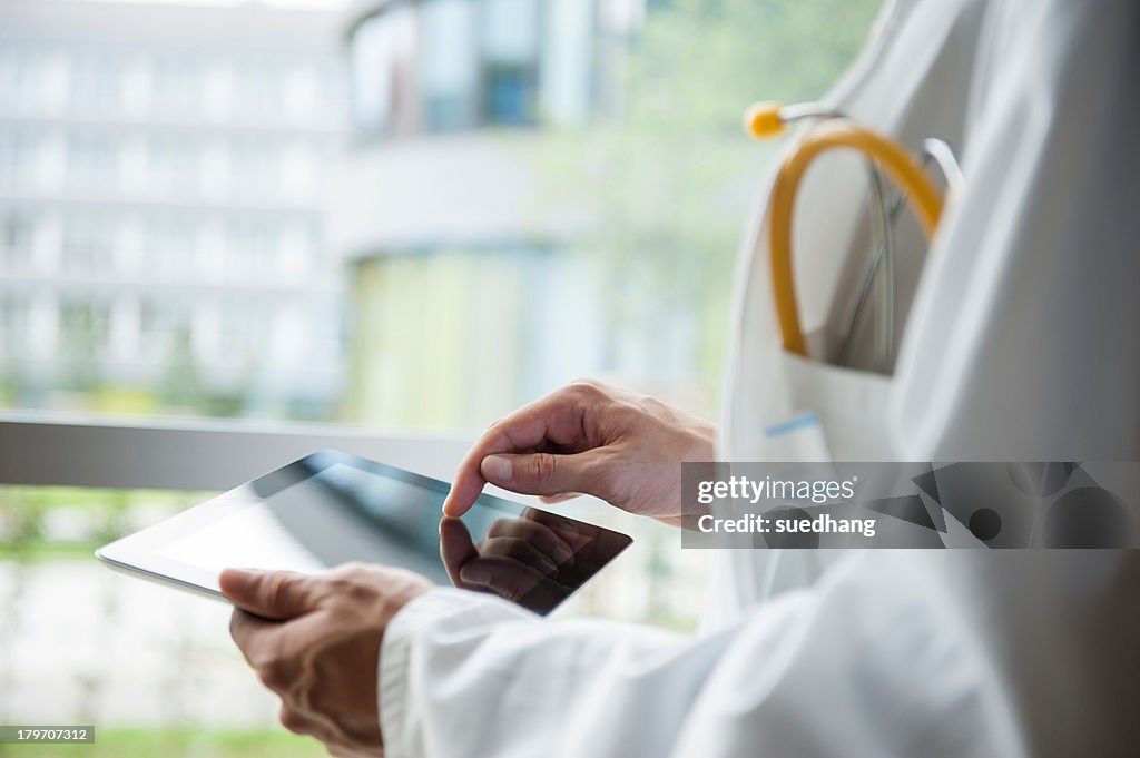 Close up of young male doctor using digital tablet