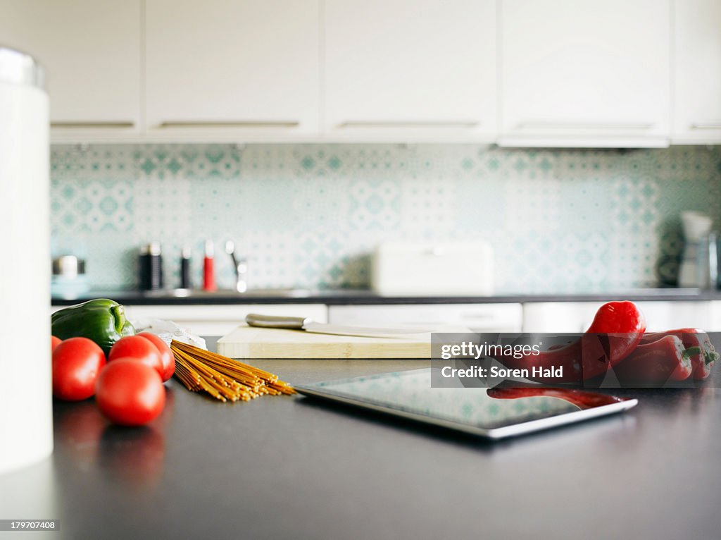 Digital tablet, red peppers and tomatoes on kitchen counter