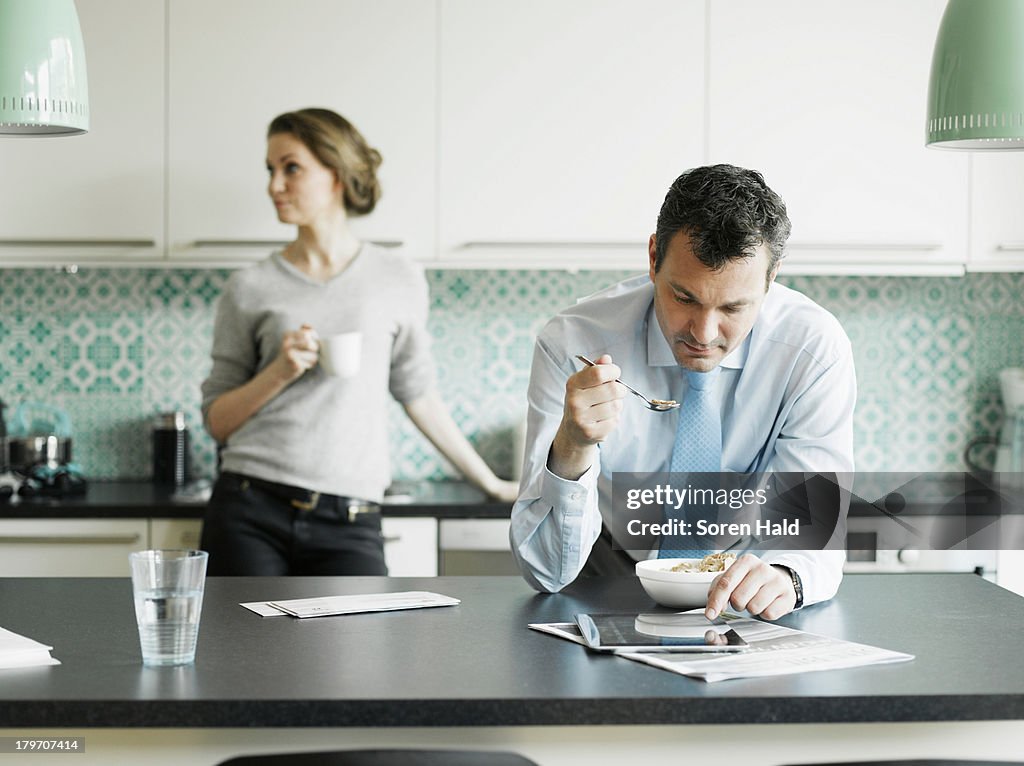 Mature businessman using tablet over breakfast in kitchen