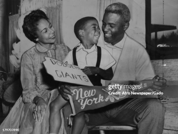 American baseball player Jackie Robinson , formerly of the Brooklyn Dodgers, and his four-year-old son David laugh it up in the trophy room of their...