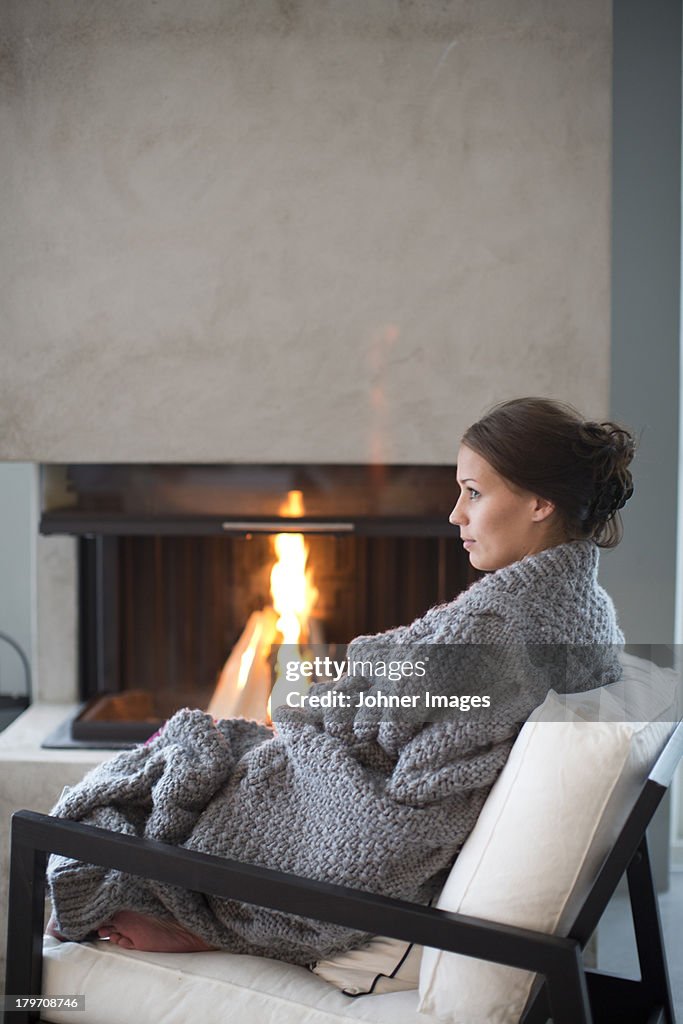 Young woman sitting in front of fireplace