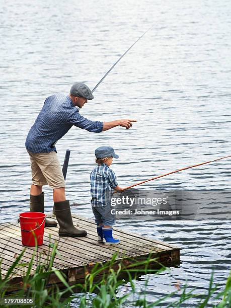 father with son fishing on jetty - angel stock-fotos und bilder