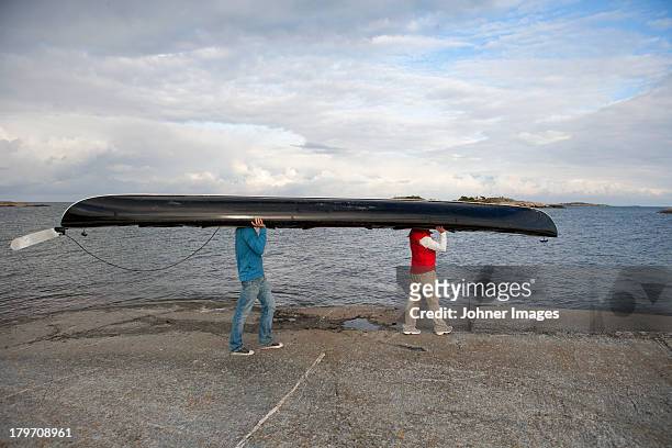 two people carrying canoe at sea - carrying canoe stock pictures, royalty-free photos & images