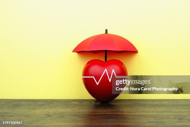 heart shape under red umbrella - medical insurance stock pictures, royalty-free photos & images