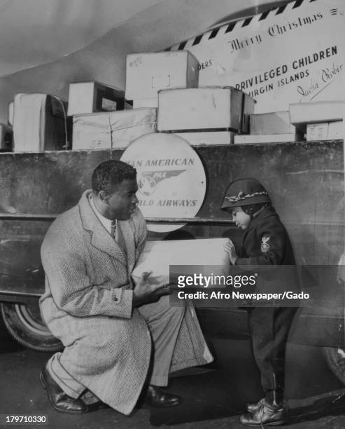American baseball player Jackie Robinson of the Brooklyn Dodgers and his son, Jackie Jr, at La Guardia prepare to send Christmas packages to...