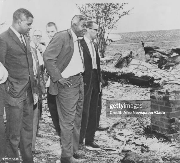 American baseball player Jackie Robinson of the Brooklyn Dodgers and other men look at a rundown area, 1955.