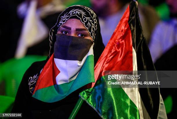An Iraqi woman looks on holding Palestinian flags during a demonstration in support of the Palestinian people in Tahrir Square in the centre of...