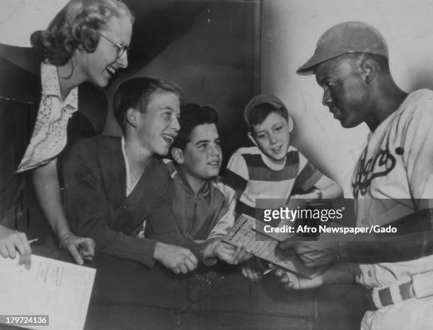 Young white fans are excited to get the autograph of American baseball player Jackie Robinson of the Brooklyn Dodgers in his wearing his Dodger...
