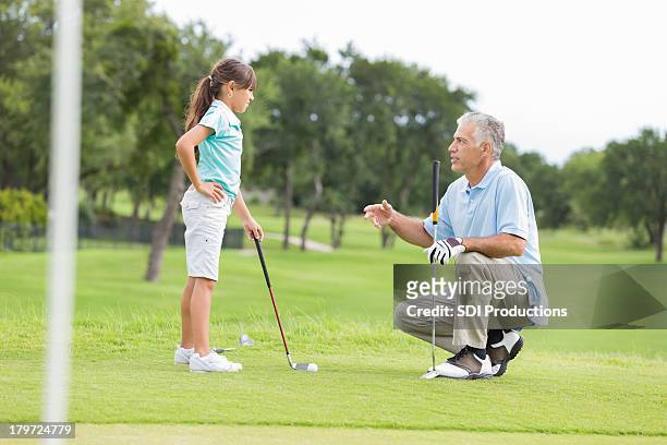 little girl taking golf lessons from professional instructor - golf girls stock pictures, royalty-free photos & images