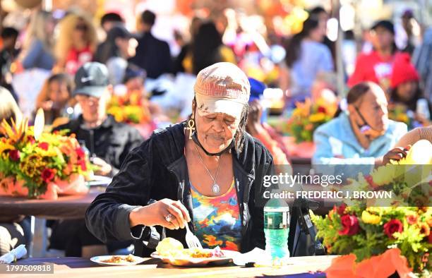 Woman enjoys her plate of food during the annual LA Mission Thanksgiving meal on Skid Row in Los Angeles, California on November 22, 2023. Over 3,000...