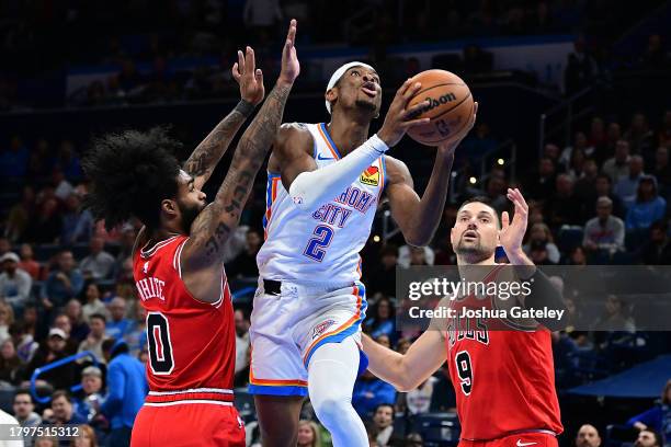 Shai Gilgeous-Alexander of the Oklahoma City Thunder goes to the basket between Coby White and Nikola Vucevic of the Chicago Bulls during the second...