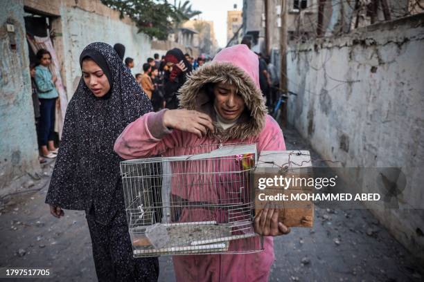 Graphic content / TOPSHOT - A girl carrying a bird cage reacts as people flee following an Israeli strike in Rafah in the southern Gaza Strip on...