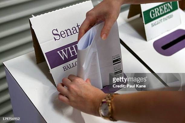 Voter places her ballot papers in the box at Huntingdale Primary School in the electorate of Hasluck on election day on September 7, 2013 in Perth,...