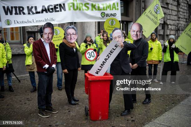 November 2023, Berlin: An activist wearing a mask of Transport Minister Wissing throws a sign with the inscription "Climate targets" into a garbage...
