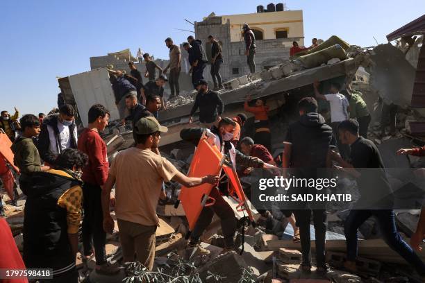 Palestinian medic walks among civilians on the rubble of a building after an Israeli strike on Rafah, in the southern Gaza Strip on November 23 amid...